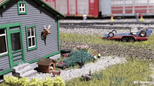 Detailed model railroad scene depicting a cluttered front yard